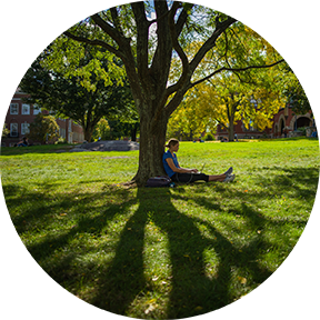 UNH Student seated on lawn on UNH Campus